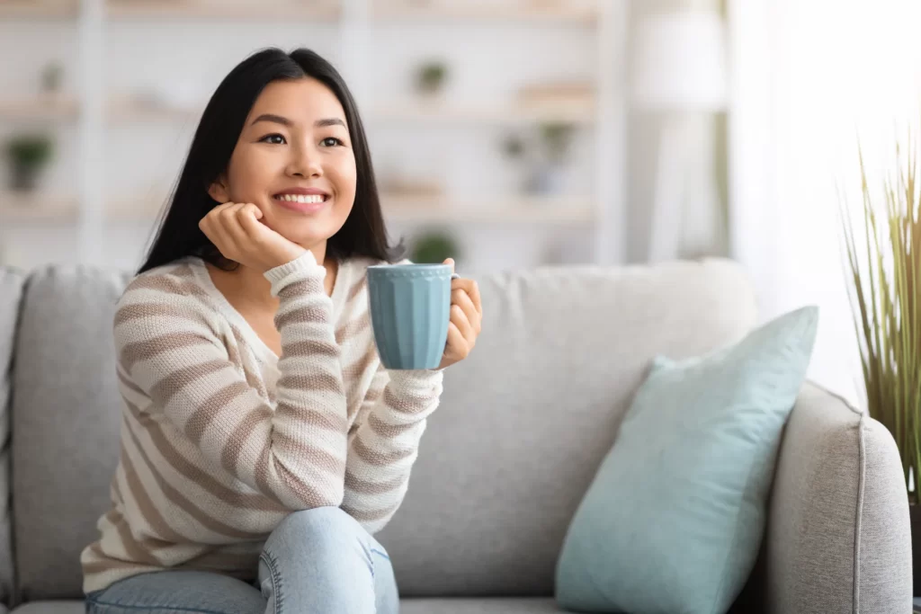 smiling woman relaxing at home with warm beverage utc